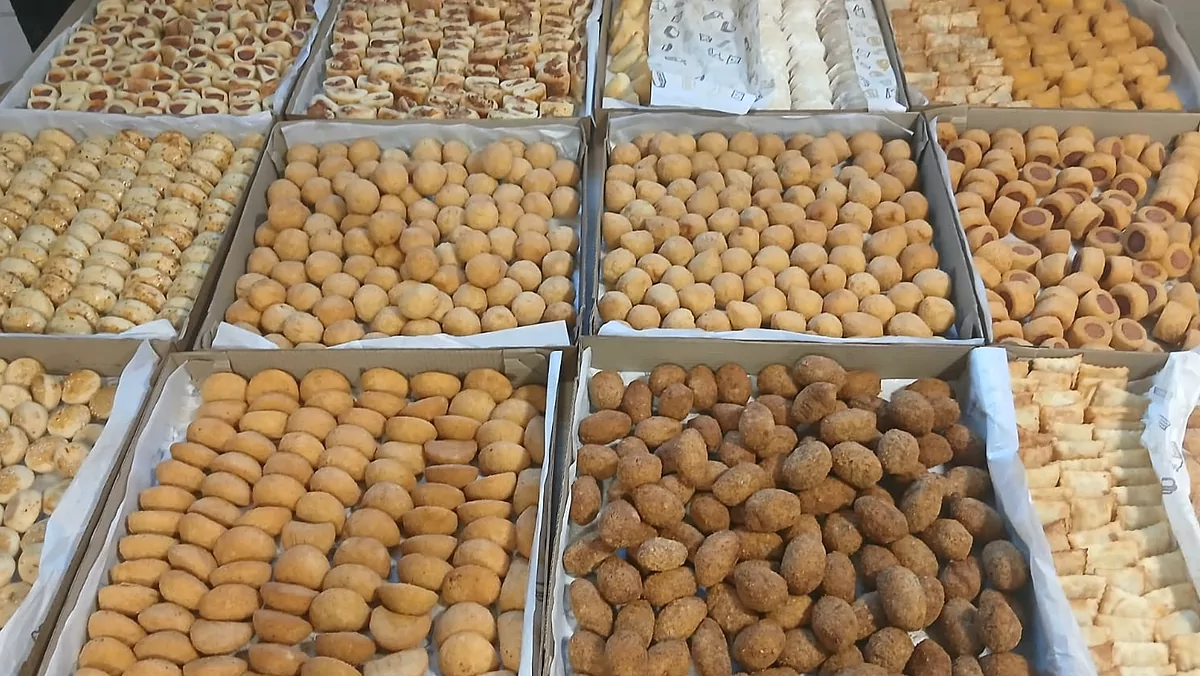 Onze caixas de salgados prontas sobre a mesa, entre fritos e assados, de uma encomenda para festa